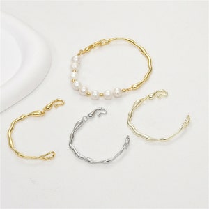 May include: Three gold bracelets with a unique, abstract design. One bracelet features a row of white pearls.