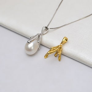 May include: Two pendants on a white surface. One is silver with a teardrop-shaped pearl, suspended from a delicate chain. The other is a gold-colored pendant with an abstract design. The pendants are examples of jewelry.