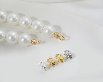 May include: A strand of white pearl beads with gold and silver bead caps. The caps are small and round with a loop for attaching to a necklace or bracelet.
