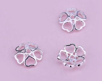 May include: Three silver flower-shaped bead caps with an open center hole. The caps are designed to hold a bead in place.