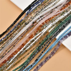 May include: Assortment of square gemstone beads in various colors, including black, blue, green, brown, white, pink, and purple. The beads are arranged in rows, creating a colorful and textured pattern.