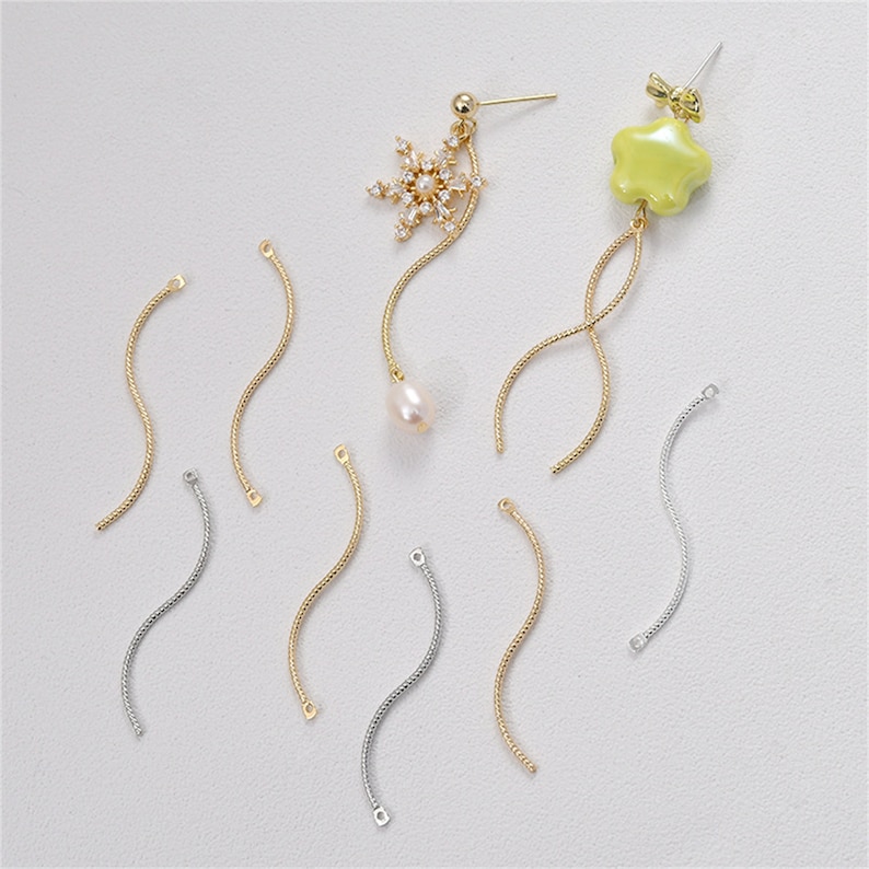 May include: A set of gold and silver chain connectors for jewelry making. The connectors are in the shape of a curved line. There are 8 connectors in total.