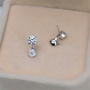 May include: A pair of silver earrings with a clear round stone and a small silver post.