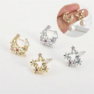Puede incluir: Un conjunto de cuatro pendientes con un diseño de media luna y estrella con detalles florales y pedrería transparente y morada.