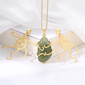 Peut inclure: Colliers dorés avec pendentifs. L'un présente une pierre verte semblable à du jade, les autres ont des motifs ajourés. Les pendentifs sont suspendus à de fines chaînes, mettant en valeur les détails et le savoir-faire des bijoux. Le fond est de couleur neutre.