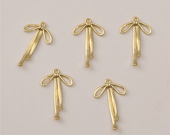 May include: Five gold-colored metal bow charms with a loop at the top for attaching to jewelry or other crafts.