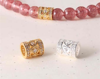 May include: Two gold and silver charm beads with a heart design and clear cubic zirconia stones. The beads are for use on bracelets or necklaces.