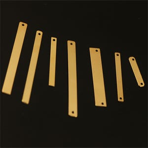 Puede incluir: Surtido de ocho formas de barra de metal de color dorado con agujeros en la parte superior. Las barras son de diferentes longitudes y anchos.