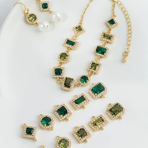 May include: A set of gold-tone jewelry featuring green and clear crystal accents. The set includes a necklace, earrings, and several connector charms.