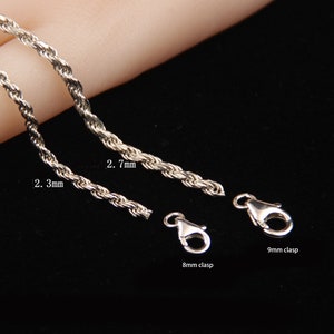 May include: Close-up of silver-colored rope chains with 2.3mm and 2.7mm thicknesses, and 8mm and 9mm clasps. The chains are displayed against a dark background, showcasing their texture and design. Jewelry.