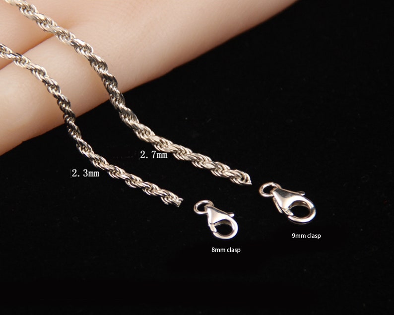May include: Close-up of silver-colored rope chains with 2.3mm and 2.7mm thicknesses, and 8mm and 9mm clasps. The chains are displayed against a dark background, showcasing their texture and design. Jewelry.