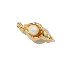 Op de afbeelding: Een goudkleurige schelpenbedel met een witte parel erin. De bedel heeft een kleine lus om aan een ketting of armband te bevestigen. De schelp is gedetailleerd met ribbels en rondingen, en de parel is glad en rond.