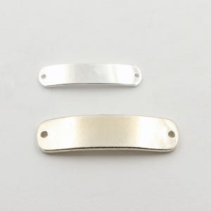 May include: Two metal blank nameplate tags. The top tag is silver and the bottom tag is gold.
