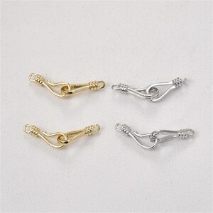May include: Four gold and silver metal clasps with a hook design. The clasps are used for jewellery making.