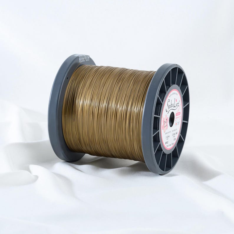 May include: A spool of gold-colored wire, labeled "SokuLine", is displayed against a white background. The wire is tightly wound around a gray plastic spool. The label on the spool is pink and white.