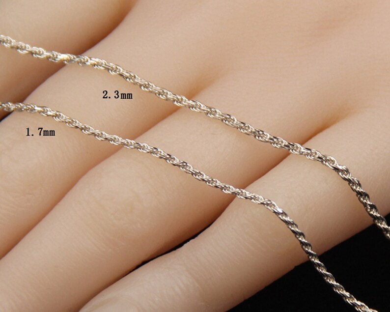 May include: Close-up of two silver-colored rope chains. One chain is labeled 1.7 mm, and the other is labeled 2.3 mm. The chains are displayed against a neutral background, highlighting their texture and design. The chains are likely for necklaces or bracelets.