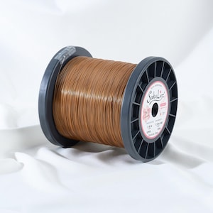 May include: A spool of copper-colored wire. The wire is tightly wound around a dark gray plastic spool. The label on the spool reads "SakuLuz" and includes details about the wire's composition and dimensions.