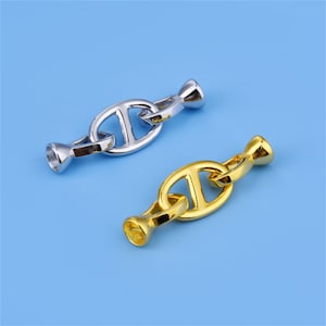 Puede incluir: Dos conectores de cadena de metal, uno plateado y otro dorado. Los conectores tienen forma de eslabón de cadena de ancla náutica.