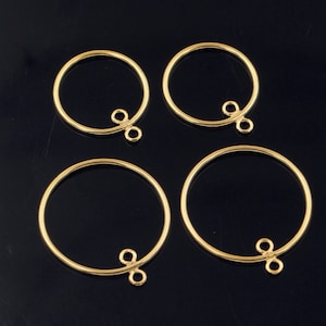 Op de afbeelding: Vier gouden metalen hoepels met een kleine lus aan de zijkant. De hoepels zijn perfect voor het maken van sieraden of knutselen.