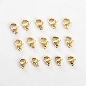 May include: A set of 18 gold-toned metal lobster clasps for jewelry making. The clasps are in various sizes, with some being larger than others.
