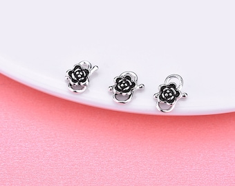 May include: Three silver-toned flower-shaped clasps with black enamel accents. The clasps are designed to be used for jewellery making.