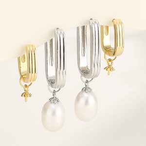 May include: A pair of hoop earrings with a pearl drop. One earring is silver and the other is gold.