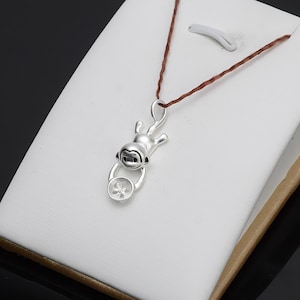 May include: Silver monkey charm pendant with a round, open-back setting for a gemstone. The monkey is holding a small circle with a flower design.