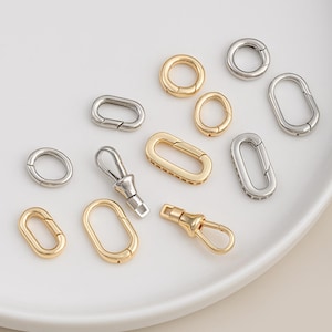 May include: An assortment of gold and silver-colored metal clasps and rings. The collection includes oval and circular clasps, along with swivel clasps, perfect for jewelry making or crafting projects.