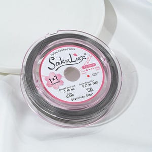May include: A spool of clear nylon-coated wire, labeled "SakuLux," with details including the diameter of 0.40 mm and a length of 100 m. The label also indicates it is made of stainless steel and has 7 strands.