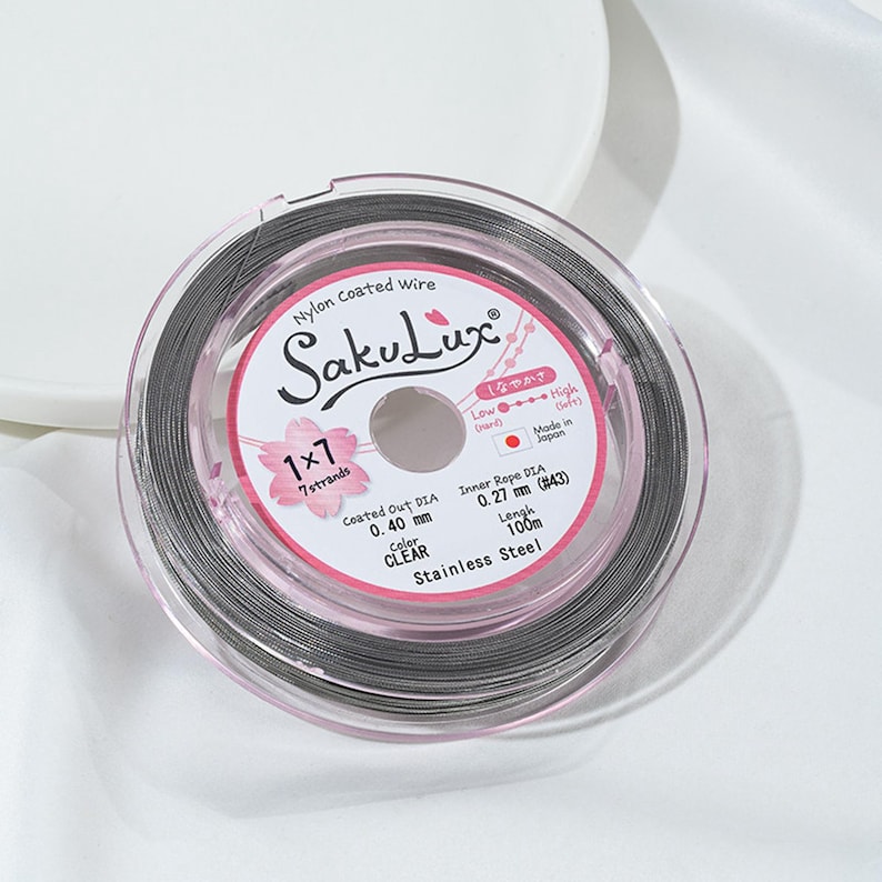 May include: A spool of clear nylon-coated wire, labeled "SakuLux," with details including the diameter of 0.40 mm and a length of 100 m. The label also indicates it is made of stainless steel and has 7 strands.