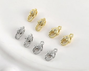 May include: A set of eight gold and silver metal clasps with a decorative floral design and a clear rhinestone in the center. The clasps are used for jewelry making.