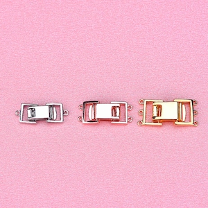 May include: Three silver, rose gold, and gold metal clasps for jewelry making. Each clasp has two loops on each side and a rectangular center piece.