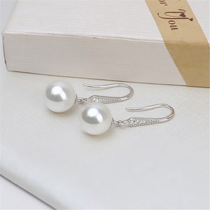 May include: A pair of silver earrings with white pearl drops. The earrings have a hook fastening.