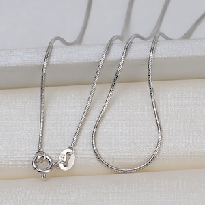Op de afbeelding: Een zilveren slangenketting met een karabijn sluiting.