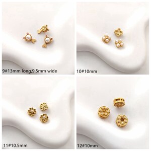 May include: Four different styles of gold-tone metal bead charms with white pearl accents. The charms are in the shape of a fish, a four-leaf clover, a flower, and a circle.
