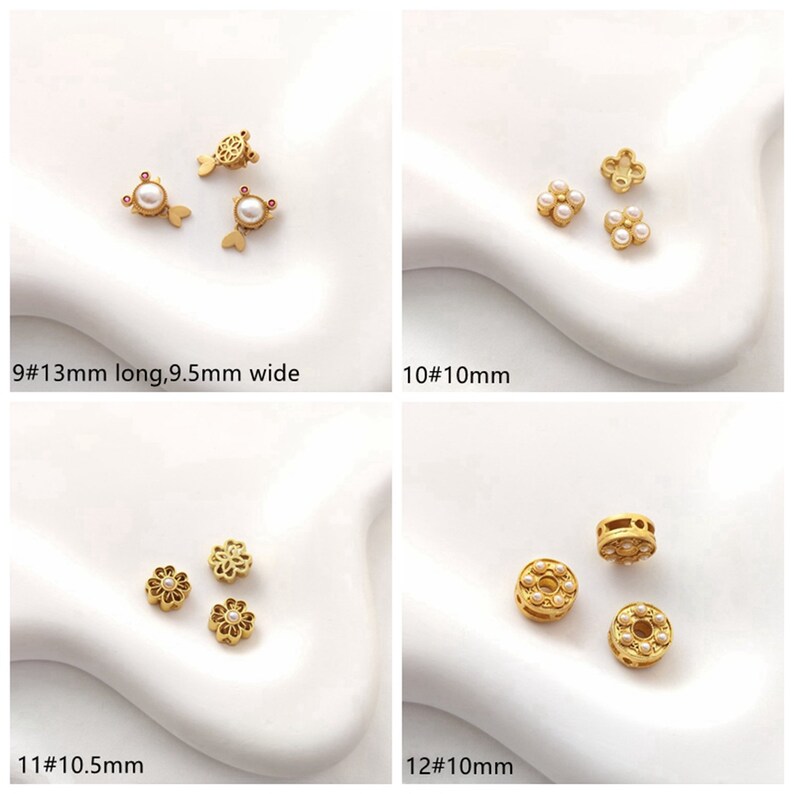 May include: Four different styles of gold-tone metal bead charms with white pearl accents. The charms are in the shape of a fish, a four-leaf clover, a flower, and a circle.
