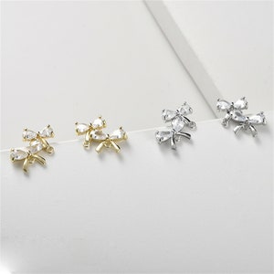 May include: Three pairs of bow-shaped jewelry connectors with clear crystal accents. The connectors are available in gold, silver, and rhodium finishes.