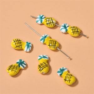Può includere: Sei ciondoli a forma di ananas in ceramica gialla e verde con anelli in filo d'argento. I ciondoli sono perfetti per aggiungere un tocco tropicale a gioielli o artigianato.