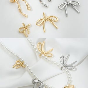 May include: A set of gold and silver bow-shaped charms. The charms are in various sizes and styles, including a single bow, a double bow, and a bow with tails. The charms are shown on a white background.