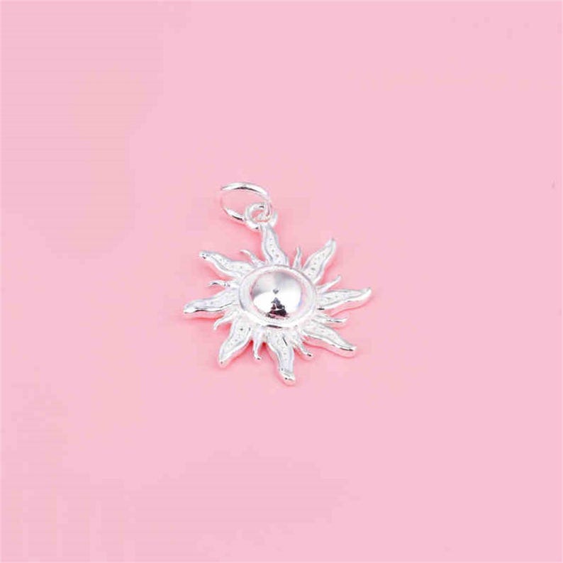 Puede incluir: Encanto de sol de plata con un dise&ntilde;o detallado. El encanto es un sol estilizado con rayos que se extienden desde el centro.