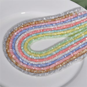 Può includere: Un set di 10 fili di perline iridescenti color pastello. Le perline sono piccole e rotonde, e sono infilate su un filo trasparente. Le perline sono disposte a forma di arcobaleno, con colori che vanno dal blu chiaro al rosa chiaro.