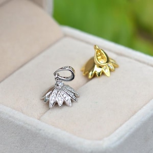 Op de afbeelding: Twee parel hanger sluitingen, een zilveren en een gouden, met een bloemvormig ontwerp en heldere kristallen.