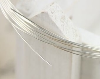 Puede incluir: Primer plano de un carrete de alambre de plata. El alambre es fino y brillante, y está enrollado firmemente alrededor del carrete.