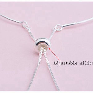 May include: A silver chain bracelet with an adjustable sliding bead. The bead is made of silicone and allows the bracelet to be adjusted to fit different wrist sizes.