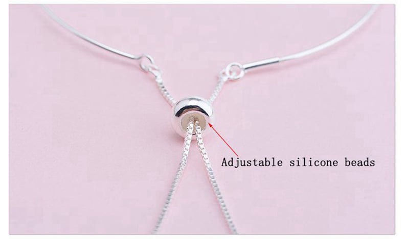 May include: A silver chain bracelet with an adjustable sliding bead. The bead is made of silicone and allows the bracelet to be adjusted to fit different wrist sizes.