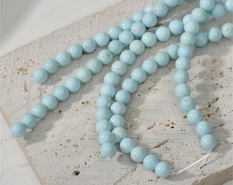 May include: A strand of light blue round beads, strung on a thin wire. The beads are smooth and uniform in size and shape.