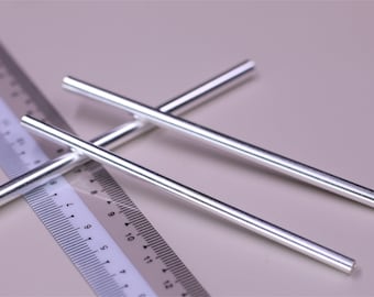 May include: Close-up of three silver metal rods, lying across a ruler. The rods are cylindrical and have a shiny, reflective surface. The ruler is white with black markings, indicating measurements in inches and centimeters. The background is a soft, neutral color.