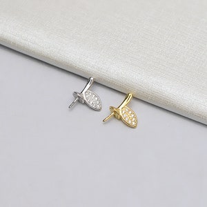 May include: Two pearl clasps, one silver and one gold, with a leaf-shaped design and clear crystal accents.