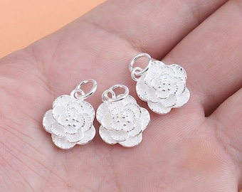 May include: Three silver flower charms with a textured surface. The charms have a loop at the top for attaching to a necklace or bracelet.
