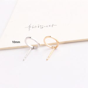 May include: Two stud earrings, one silver-toned and one gold-toned, each with a circular design. The earrings are approximately 0.4 inches in diameter. The background is a white surface with Korean text.